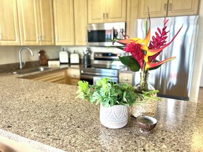 A kitchen counter with a decorative plant arrangement, a microwave, and a stainless steel refrigerator.