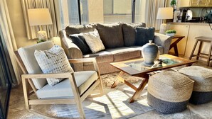 A living room with a sofa, armchair, coffee table, and ottomans.