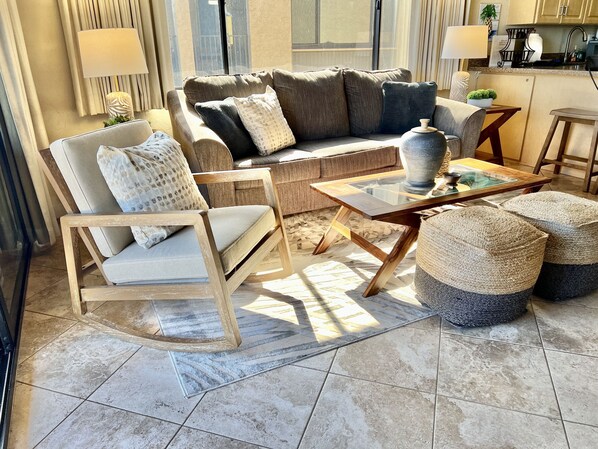 A living room with a sofa, armchair, coffee table, and ottomans.