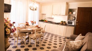 A modern kitchen with white cabinets, a dining table with chairs, and a patterned floor. - Luxury apartment residence "La Fontana" (Lucca)