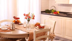 A dining table set with a coffee pot, cups, a vase with flowers, and a plate of food. - Luxury apartment residence "La Fontana" (Lucca)