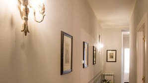 A hallway with a patterned floor, wall-mounted lights, and framed pictures. - Luxury apartment residence "La Fontana" (Lucca)