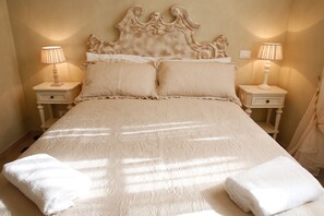 Una cama con cabecera, dos mesitas de noche con lámparas y dos toallas sobre la cama.