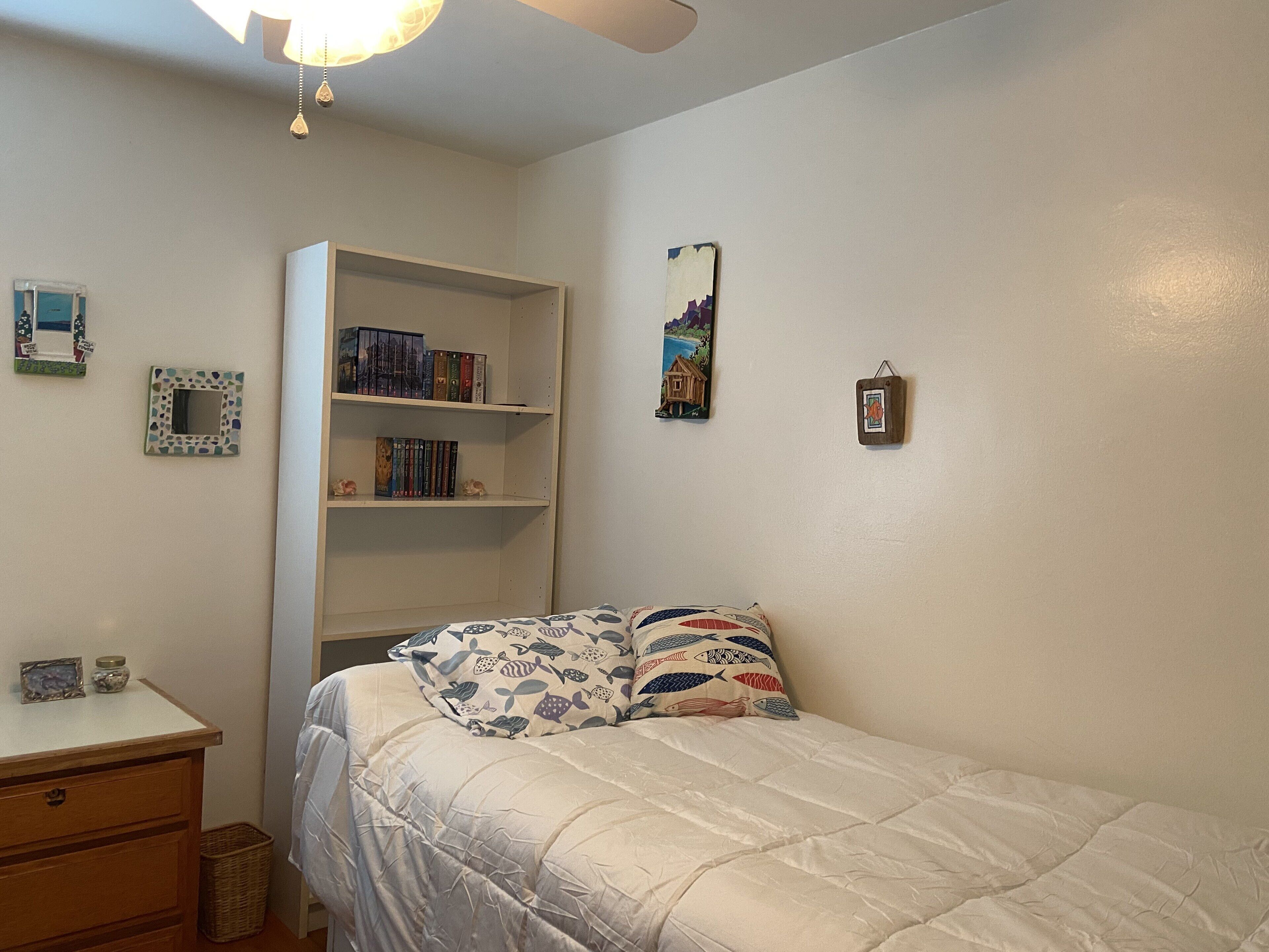 Une chambre à coucher comprenant un lit, une bibliothèque, une commode et un mur orné de tableaux.