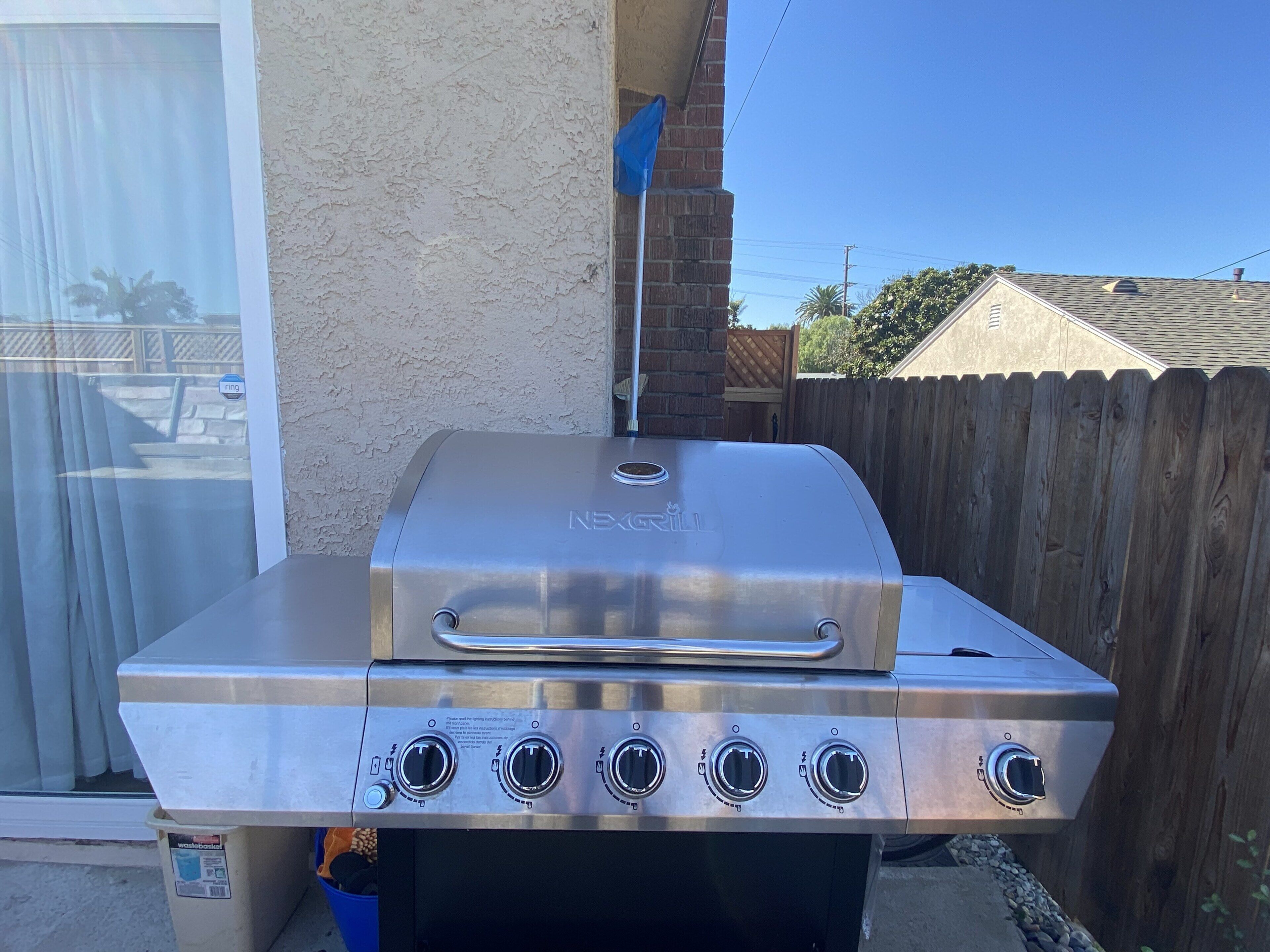 A stainless steel Weber grill with four burners, a side shelf, and a chimney starter.