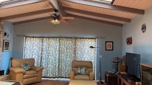 Un salon avec deux fauteuils en cuir, un canapé, un ventilateur de plafond et un téléviseur.