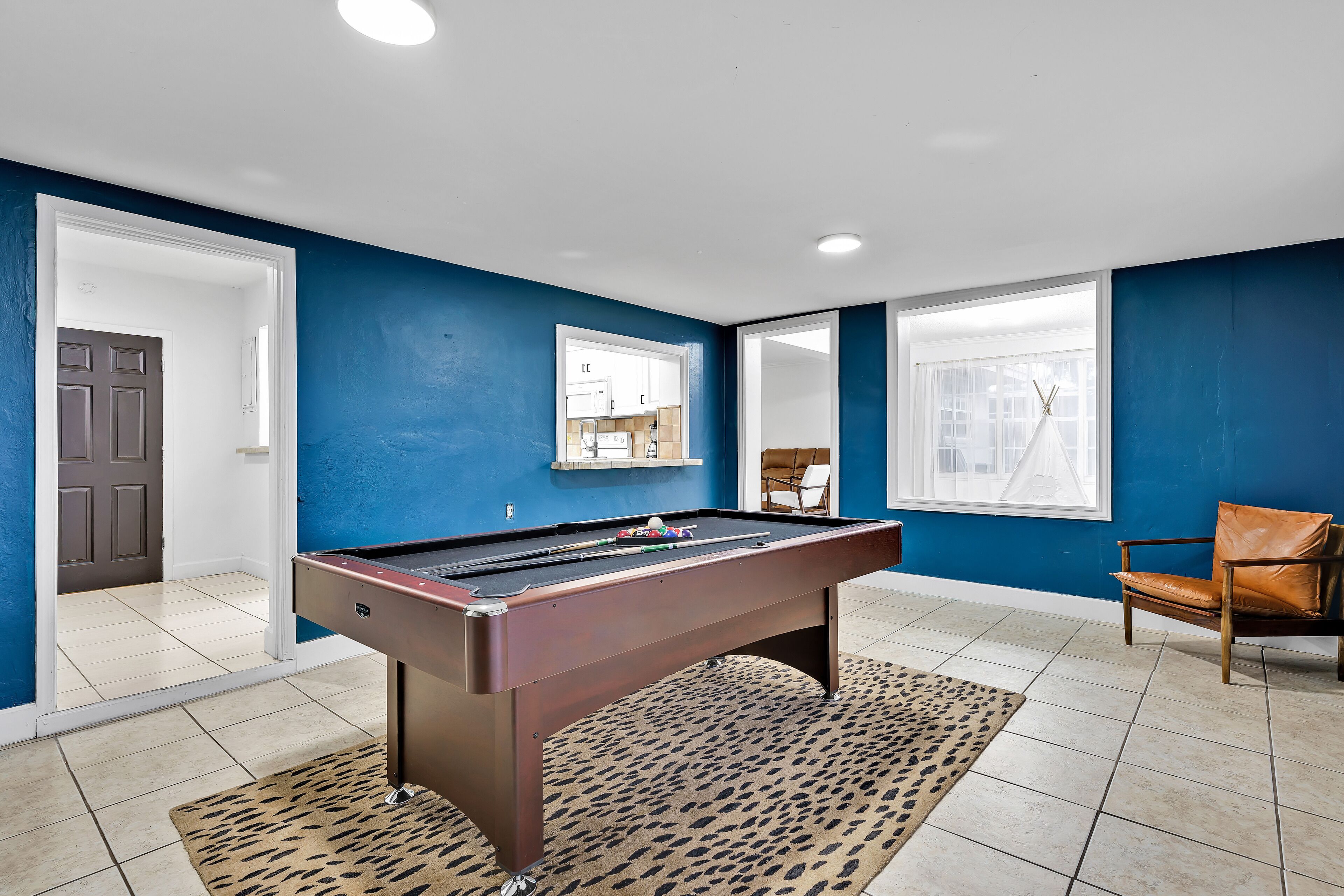 A pool table in a room with blue walls, a window, and a door.