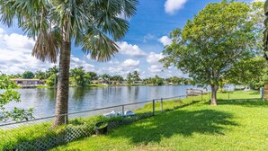 A park with a lake, a palm tree, and a grassy area with a fence. - Private lakefront charming Home in Miami/Pembroke (Pembroke Pines)