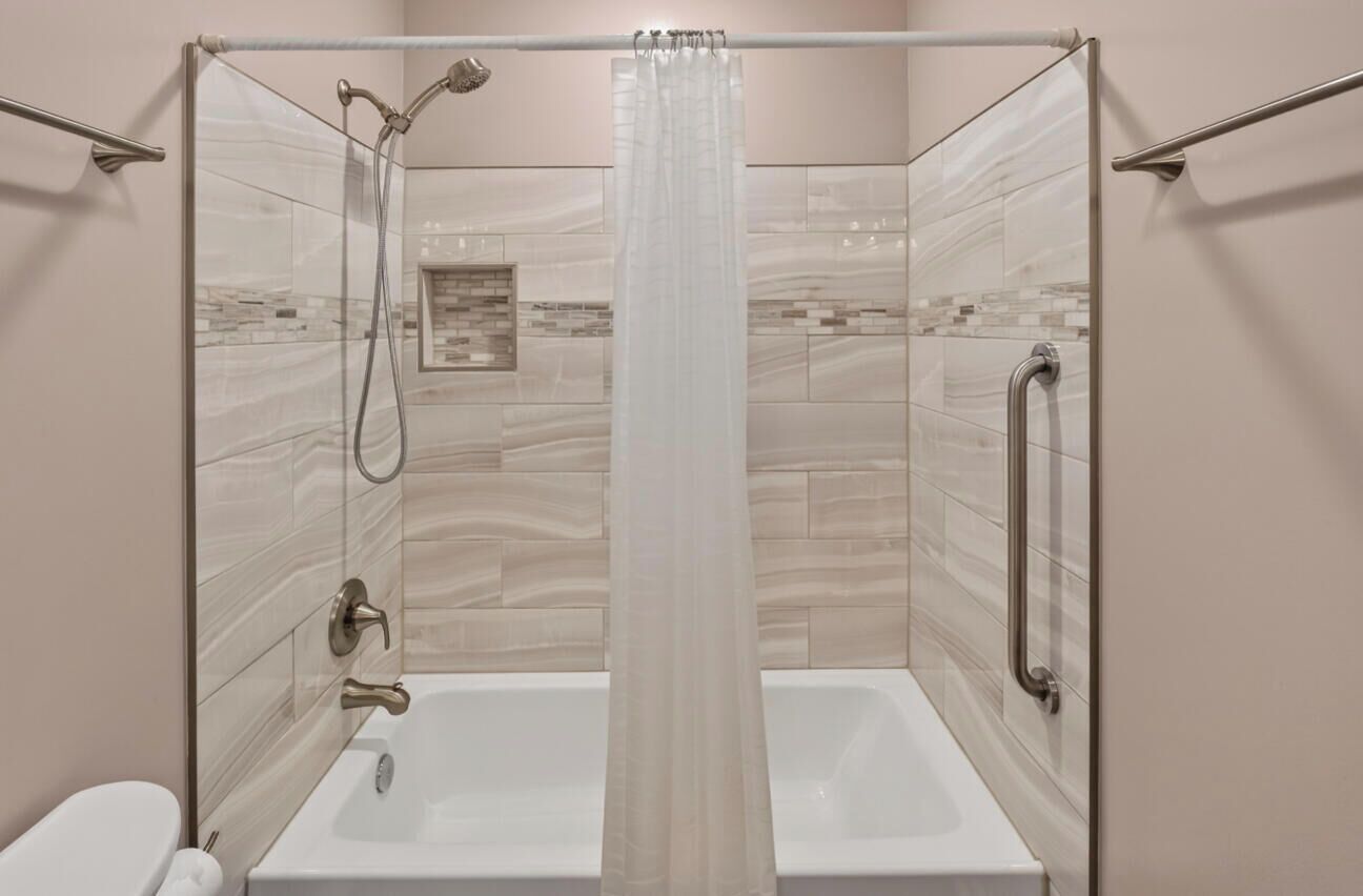 Een douche met glazen deur, een bad en een toilet.