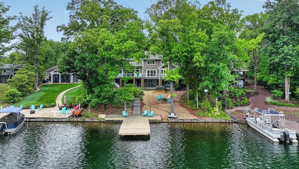 A lakeside property with a dock, outdoor seating, and a house with a deck. - Beautiful, spacious, lakefront home large lot, firepit, hot tub, and more  (Locust Grove)