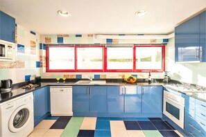 A kitchen with a washing machine, dishwasher, and a window with red frames.