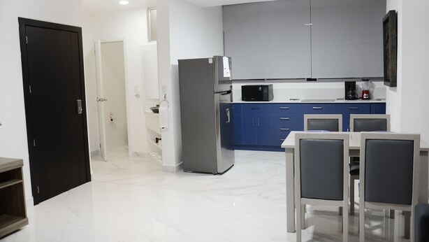 A modern kitchen with a refrigerator, microwave, and blue cabinets.
