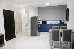 A modern kitchen with a refrigerator, microwave, and blue cabinets.