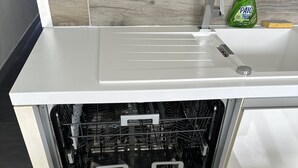 Un lave-vaisselle Whirlpool avec une finition en acier inoxydable, un panneau de commande doté de différents réglages et un panier à couverts à l’intérieur.