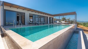 A modern pool area with clear blue water, a pergola, and lounge chairs. - Messinian Riviera Villas (Petalidi)
