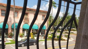 Varanda com vista para uma rua, carros e um edifício com toldos verdes.