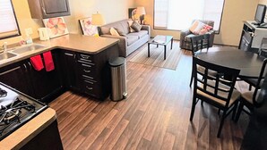 A compact living space with a kitchenette, a dining area, and a seating area with a sofa and chairs.