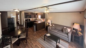 A compact living space with a kitchenette, a dining area, and a seating area with a sofa and coffee table.