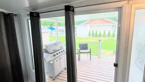 A room with a sliding glass door leading to an outdoor deck with a grill and patio furniture.