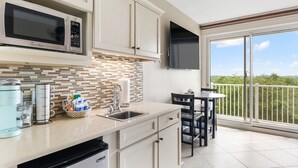 A modern kitchen with a microwave, sink, and a dining area with a view of the outdoors. - Beachy Sandestin studio, walk to Baytowne Wharf (Miramar Beach)