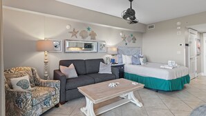 A hotel room with a sofa, a chair, a bed, a nightstand, and a ceiling fan. - Beachy Sandestin studio, walk to Baytowne Wharf (Miramar Beach)