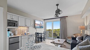 A modern hotel room with a kitchenette, a dining area, a sofa, and a large window with a view of the sea. - Beachy Sandestin studio, walk to Baytowne Wharf (Miramar Beach)
