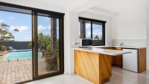 Enjoy a seamless indoor-outdoor living experience with a large island and expansive views of the outdoor pool area.