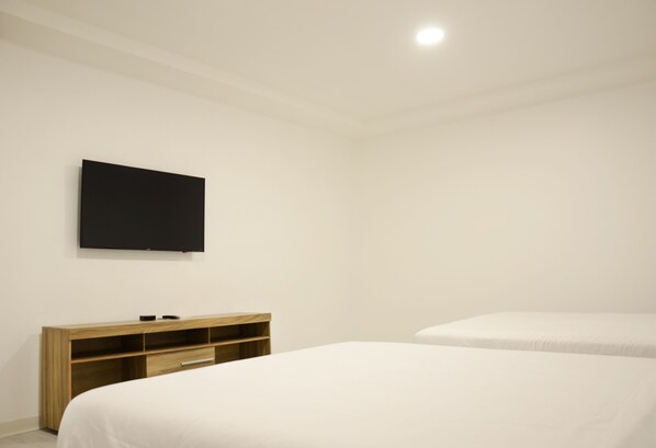 A bedroom with a bed, a TV mounted on the wall, and a wooden dresser. - Downtown Quito Family apt - 100Mbps internet (Quito)