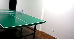 A green ping pong table in a room with a wooden floor and white walls.