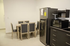 A compact kitchen with a refrigerator, microwave, and a small countertop. There is a dining table with four chairs. - Downtown Quito Family apt - 100Mbps internet (Quito)