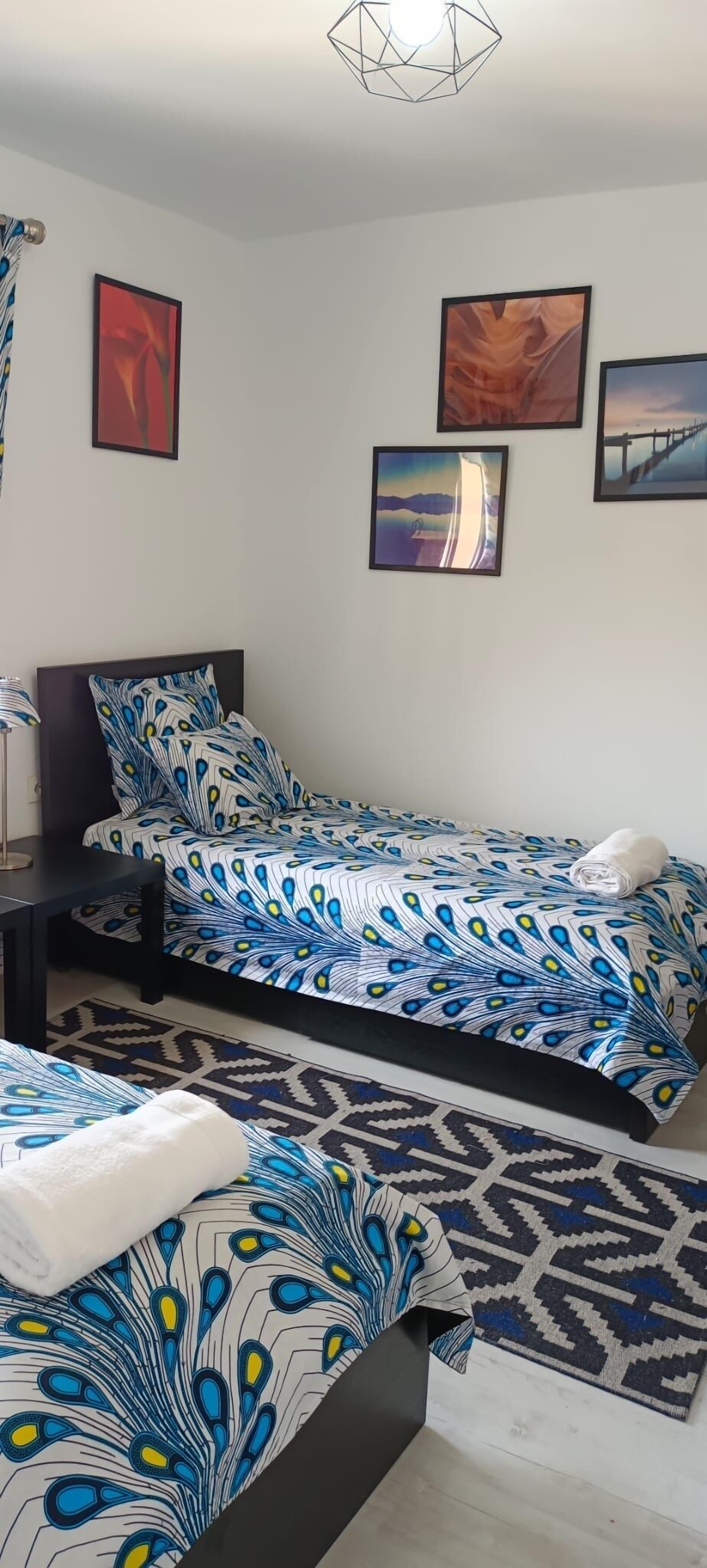 Una camera da letto con due letti, un comodino e una lampada fissata alla parete.