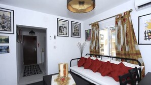 Ein Zimmer mit einem Bett, einem Tisch, einer Tür und gerahmten Bildern an der Wand.