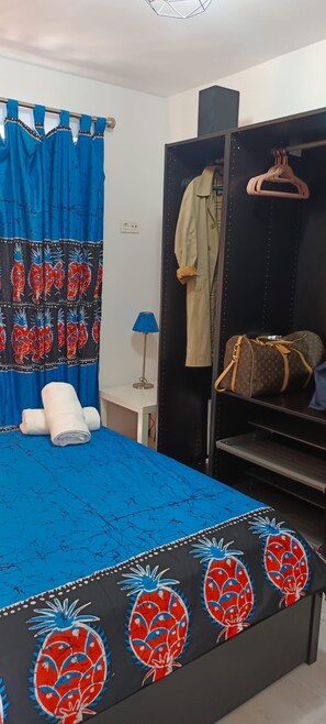 Ein Schlafzimmer mit Bett, Kleiderschrank und Kleiderstange.