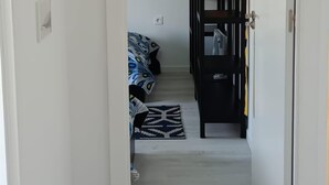 Ein Flur mit einem Bett, einem schwarzen Kleiderschrank und einer Tür zu einem anderen Raum.