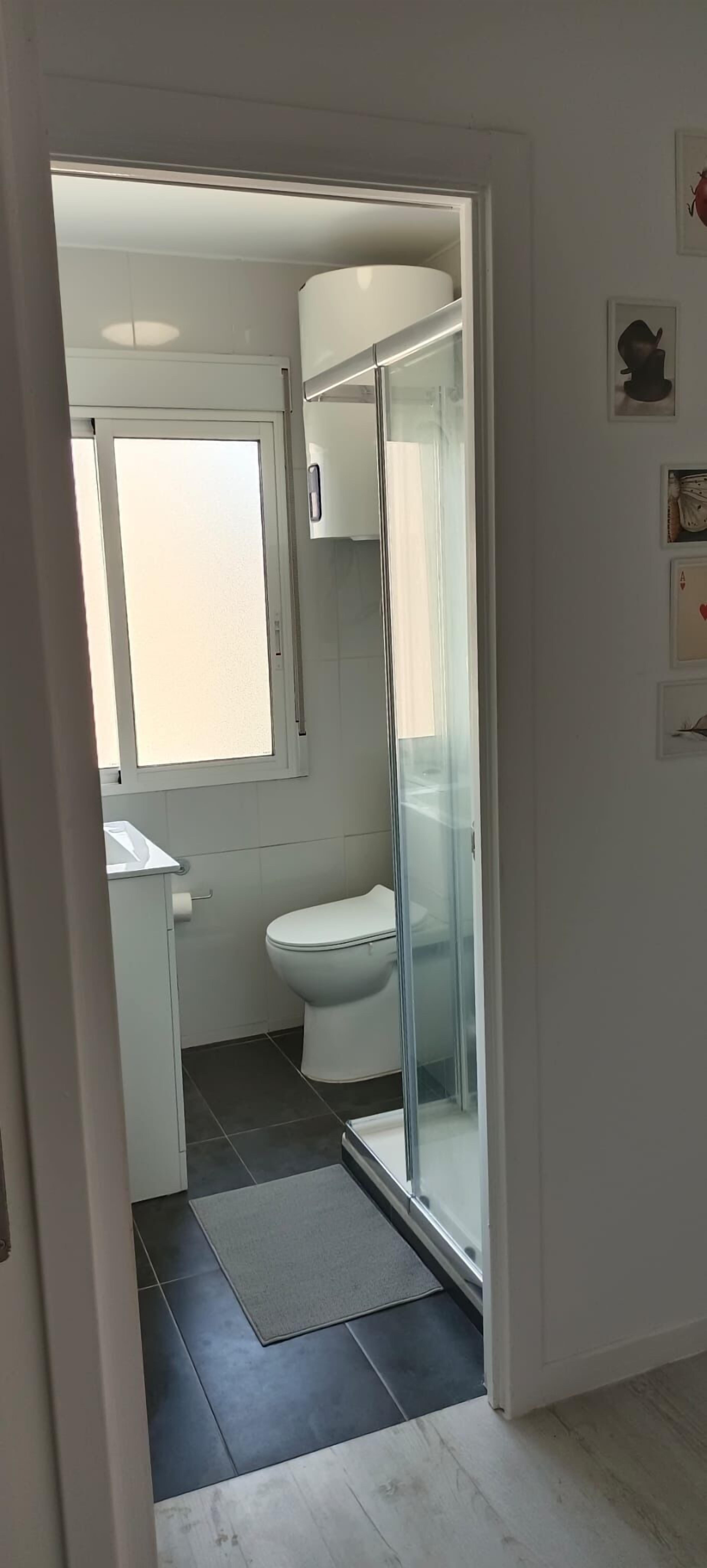 A modern bathroom with a glass shower enclosure, a toilet, and a sink.
