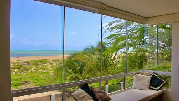 A room with a large window overlooking a beach and palm trees. - Beach Front Exclusive Villa with Pool (SAO MIGUEL DO GOSTOSO)