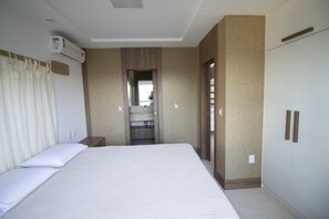 Habitación de hotel con una cama grande, armario empotrado, espejo y unidad de aire acondicionado.