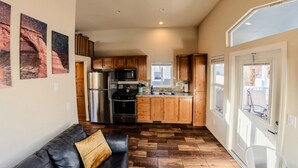 Una cocina compacta con armarios de madera, electrodomésticos de acero inoxidable y piso de madera con diseño en espiga.