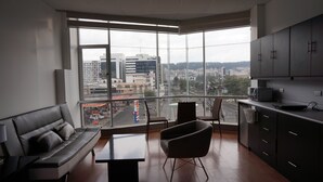 Eine moderne Wohnung mit großem Balkon, einer Couch, einem Esstisch und einer Küchenzeile.