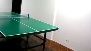Ein grüner Tischtennis-Tisch in einem Raum mit weißen Wänden und Holzboden.