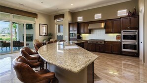 A spacious kitchen with a large island, dark wooden cabinets, and stainless steel appliances. - La Quintuta -- our home away from home (La Quinta)