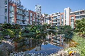 Un moderno edificio residenziale con uno stagno riflettente e verde circostante.