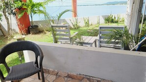 Un balcon avec un fauteuil en osier, une petite table et une vue sur un lac.