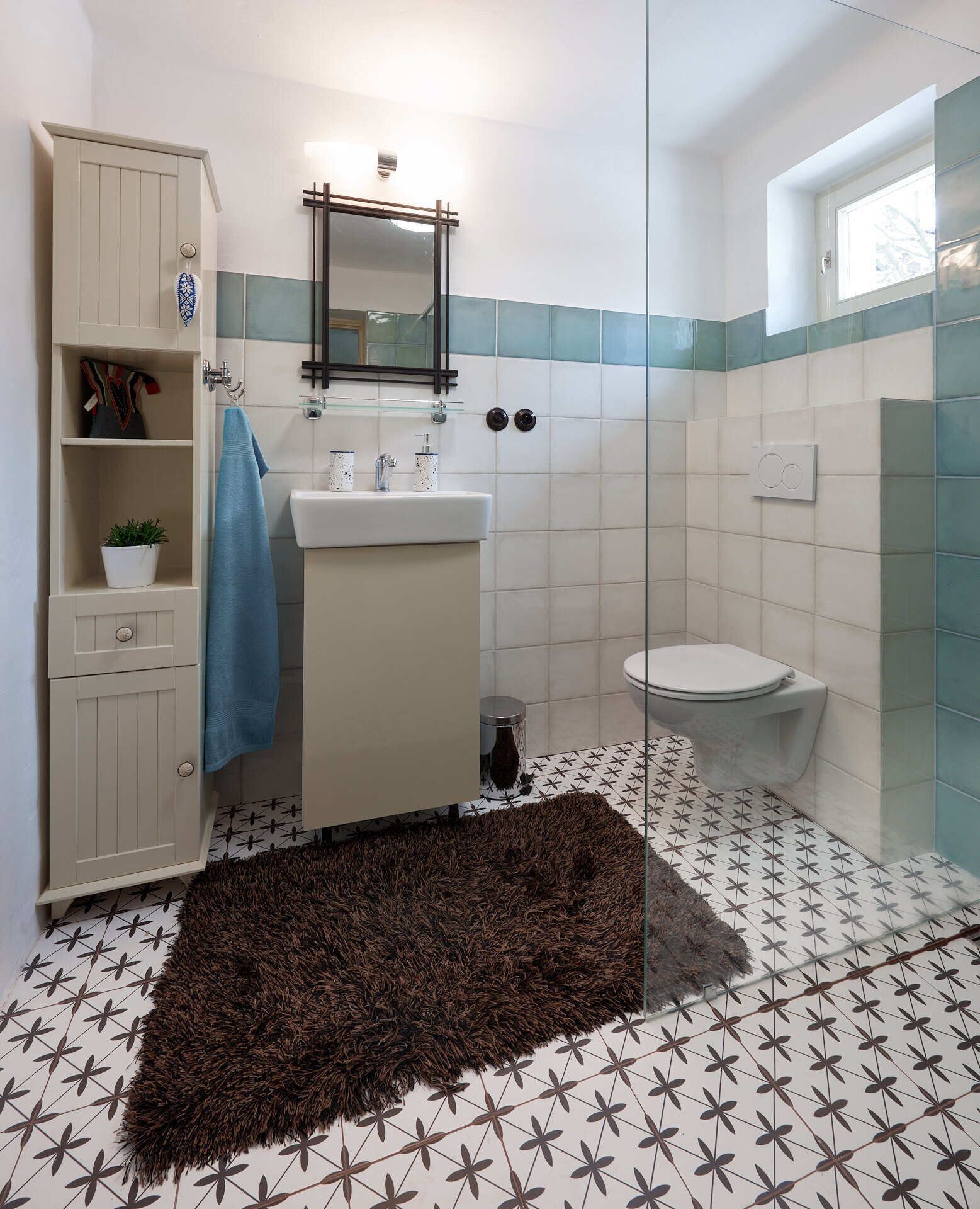 Un baño con inodoro, lavamanos, espejo y armario.
