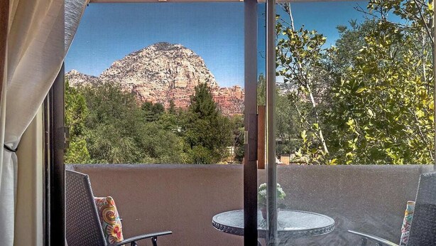 Un balcón con dos sillas y una mesa, con vista a un paisaje montañoso.