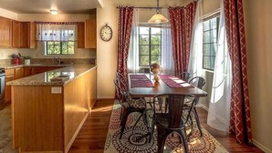 Una cocina moderna con armarios de madera, encimera de granito y comedor con mesa y sillas.