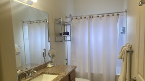 Un baño con lavamanos, espejo, inodoro y cortina de ducha.