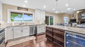 A modern kitchen with white cabinets, a large island, and a view of the outdoors. - Lofted Bluff Sunset Lake Views and Private Boat Dock (Osage Beach)
