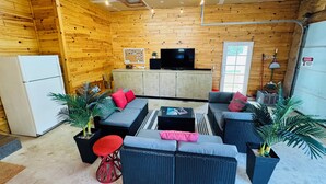 Interior acogedor de una cabaña de troncos con sofá, televisor y refrigerador.