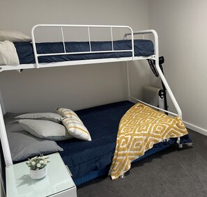 Cozy bedroom with a bunk bed setup featuring a top and bottom bunk, each with a metal frame and a comfortable mattress.